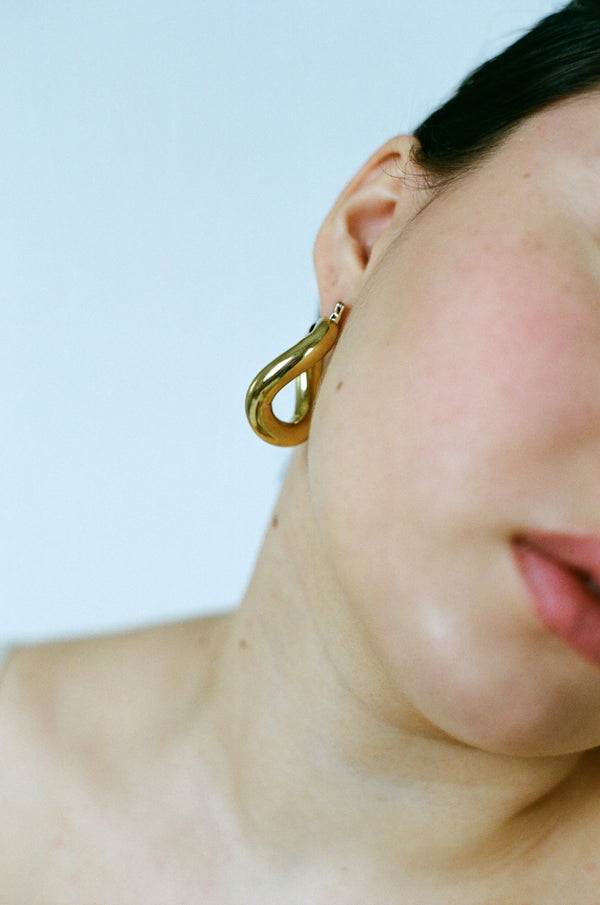 Side profile of model wearing Laura Lombardi gold Anima hoop earrings.