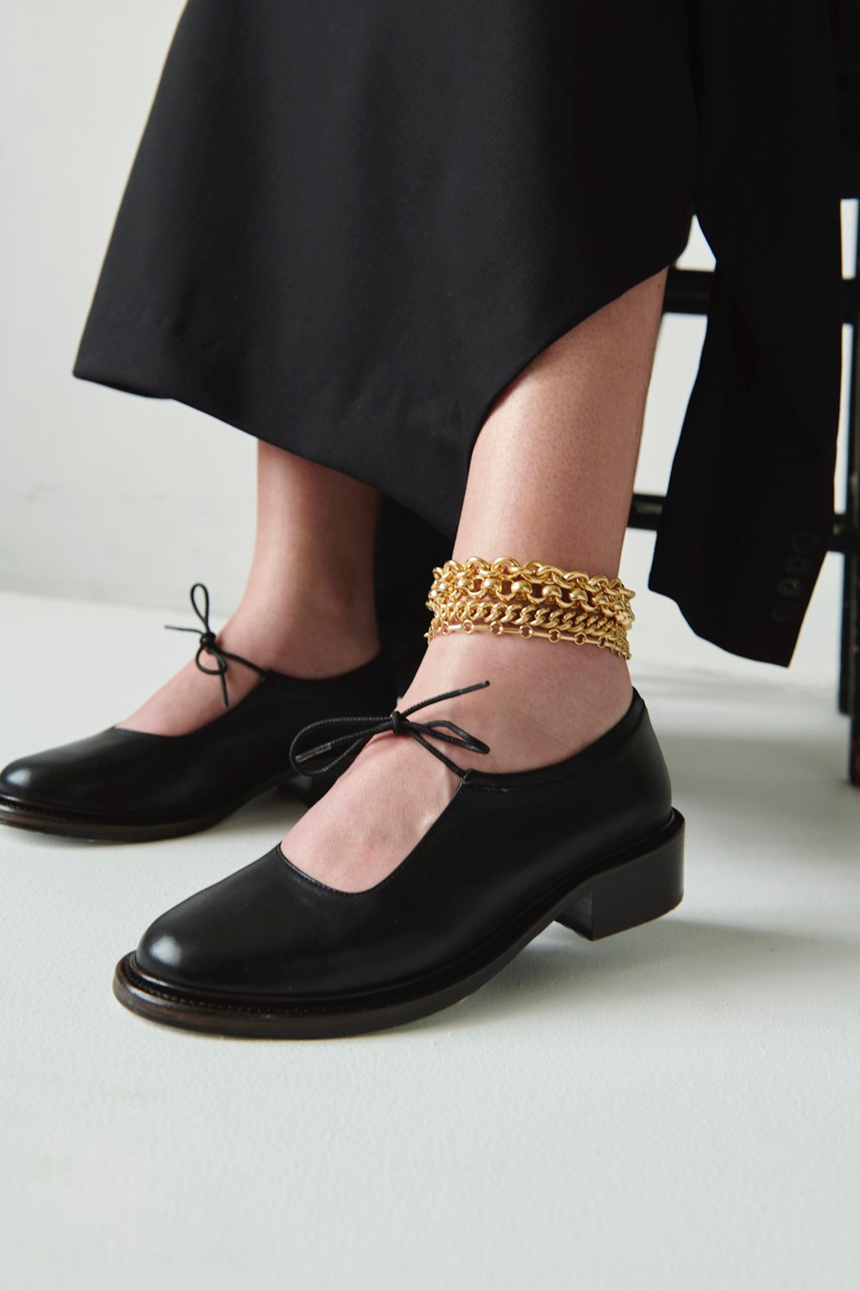 Model wearing multiple Laura Lombardi gold chain anklets.