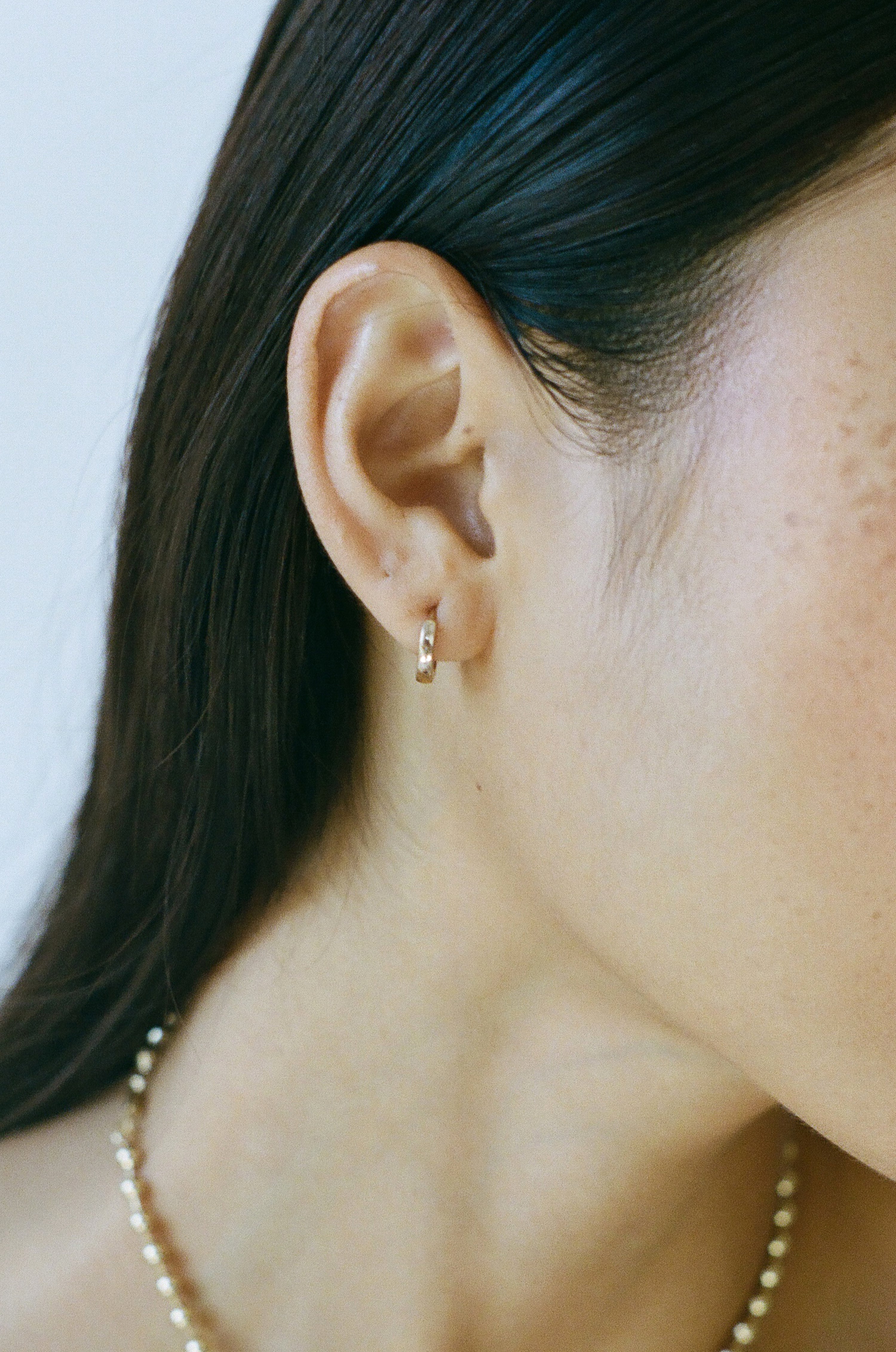 Side profile of model wearing Laura Lombardi gold Clutch Hoops.