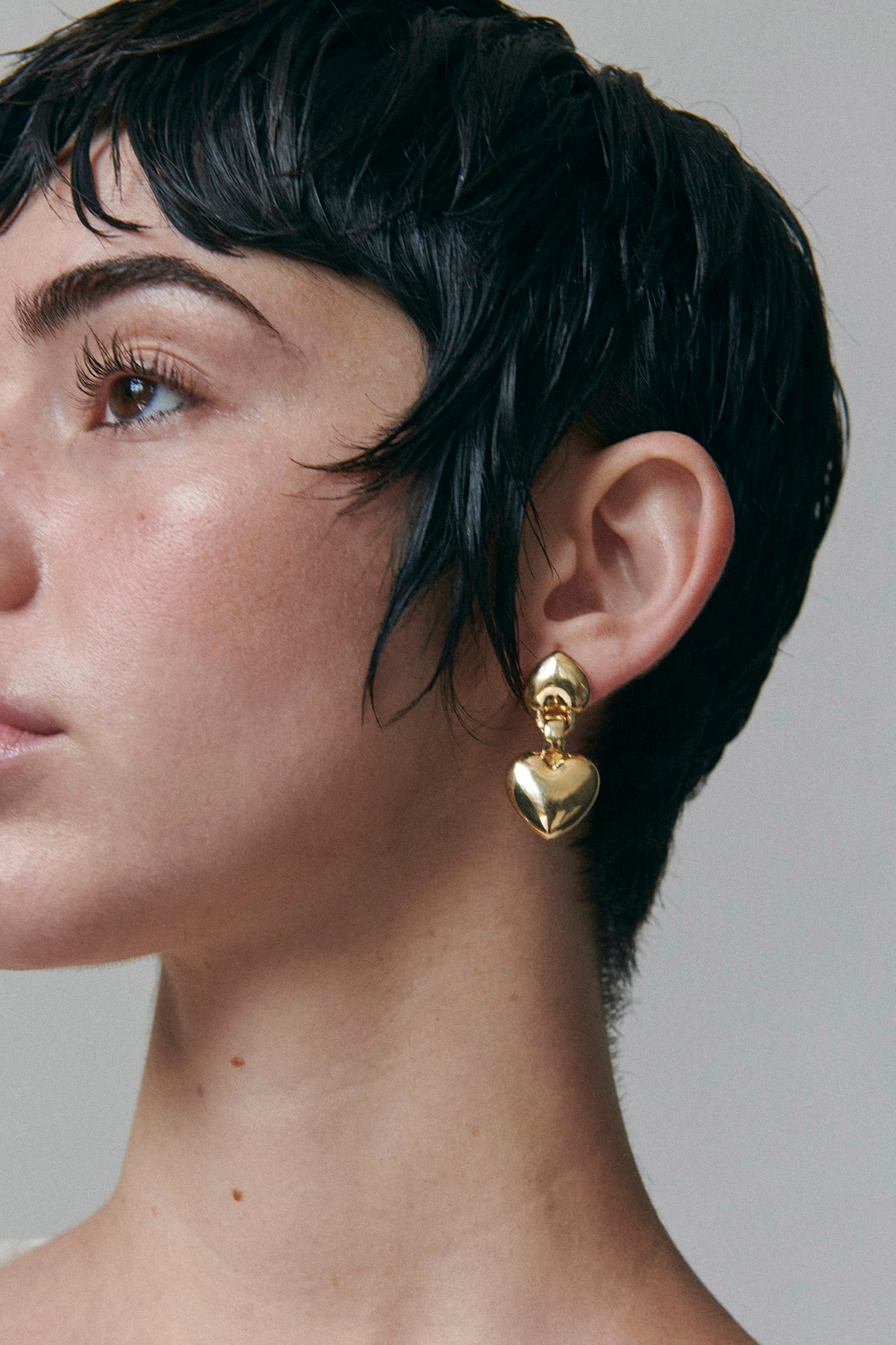 Side profile of model wearing Laura Lombardi gold double heart Chiara drop earrings.