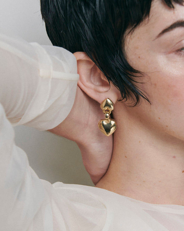 Side profile of model wearing Laura Lombardi gold double heart Chiara drop earrings.