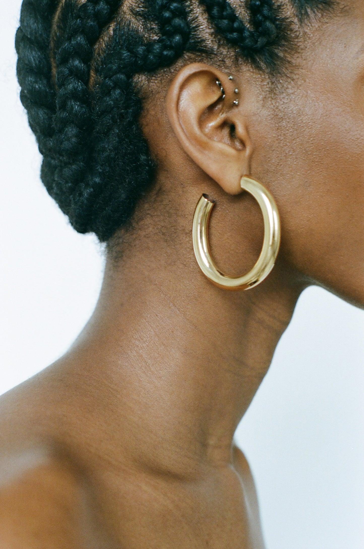 Side profile of model wearing Laura Lombardi gold Curve Hoop Earrings.