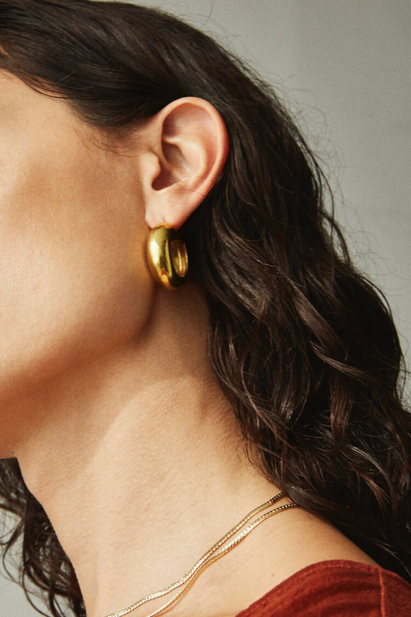 Side profile of model wearing Laura Lombardi gold domed Cusp Hoops.