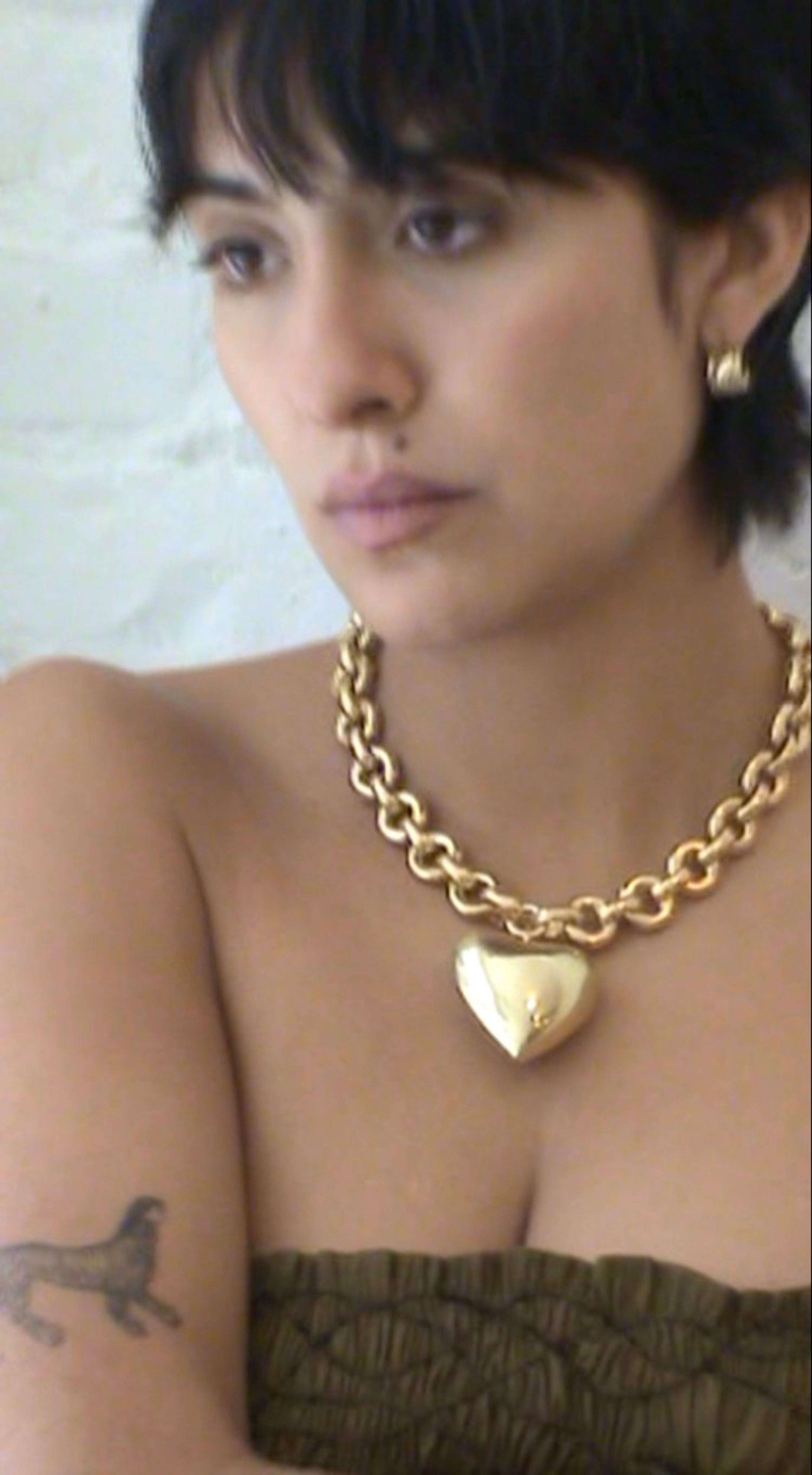 Model wearing Laura Lombardi gold Giulietta Necklace with oversized heart pendant.