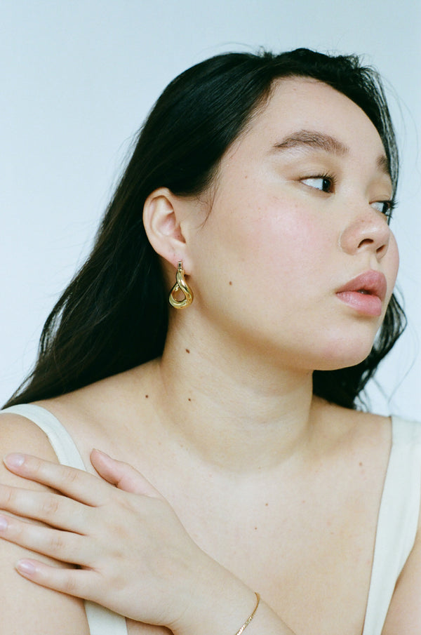 Model wearing Laura Lombardi gold sculptural Mini Anima Hoop earrings.