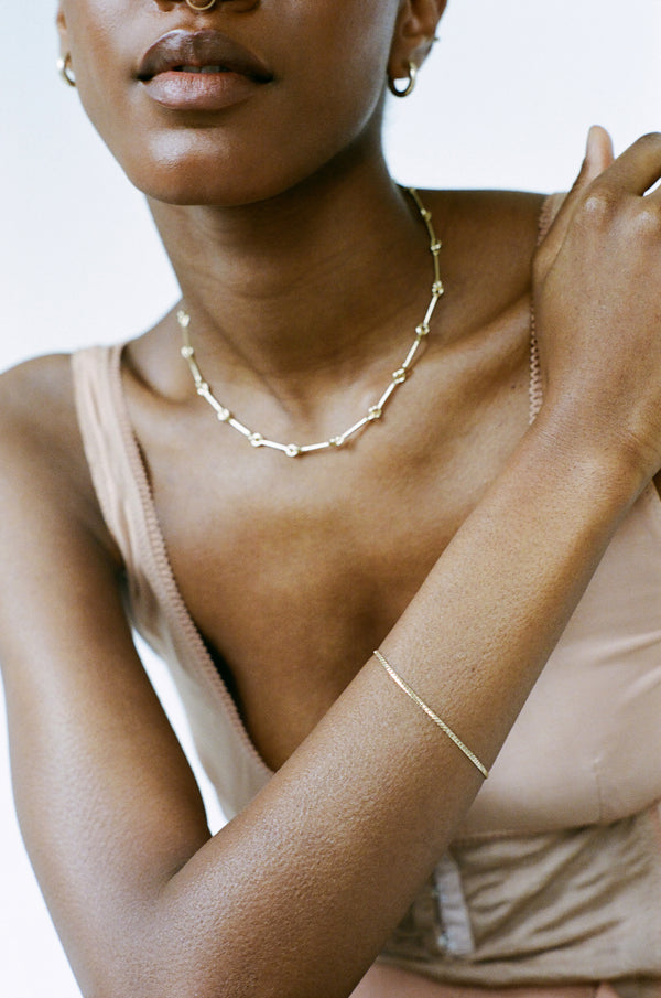 Model wearing Laura Lombardi gold Mini Omega Bracelet and Treccia Necklace.