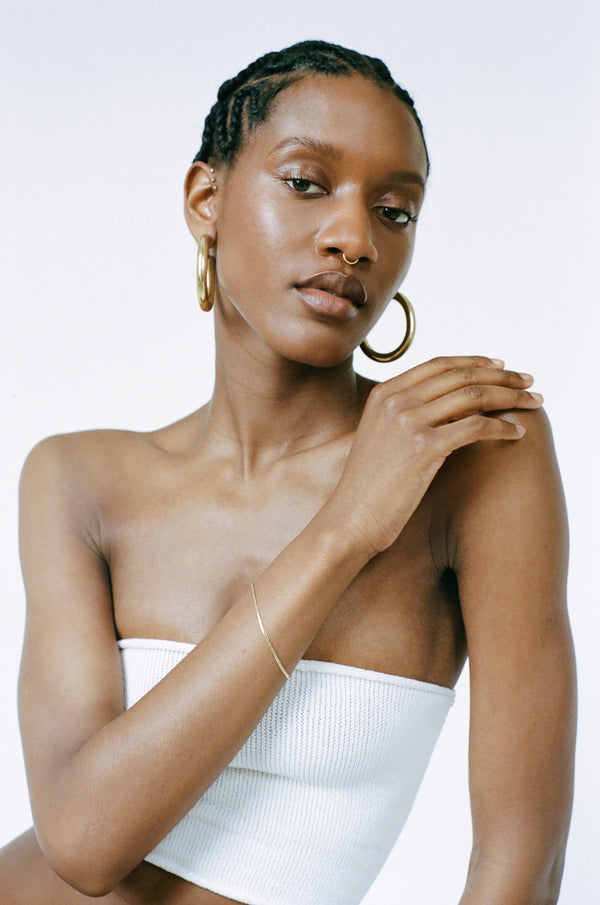 Model wearing Laura Lombardi gold Mini Omega Bracelet and XL Hoops.