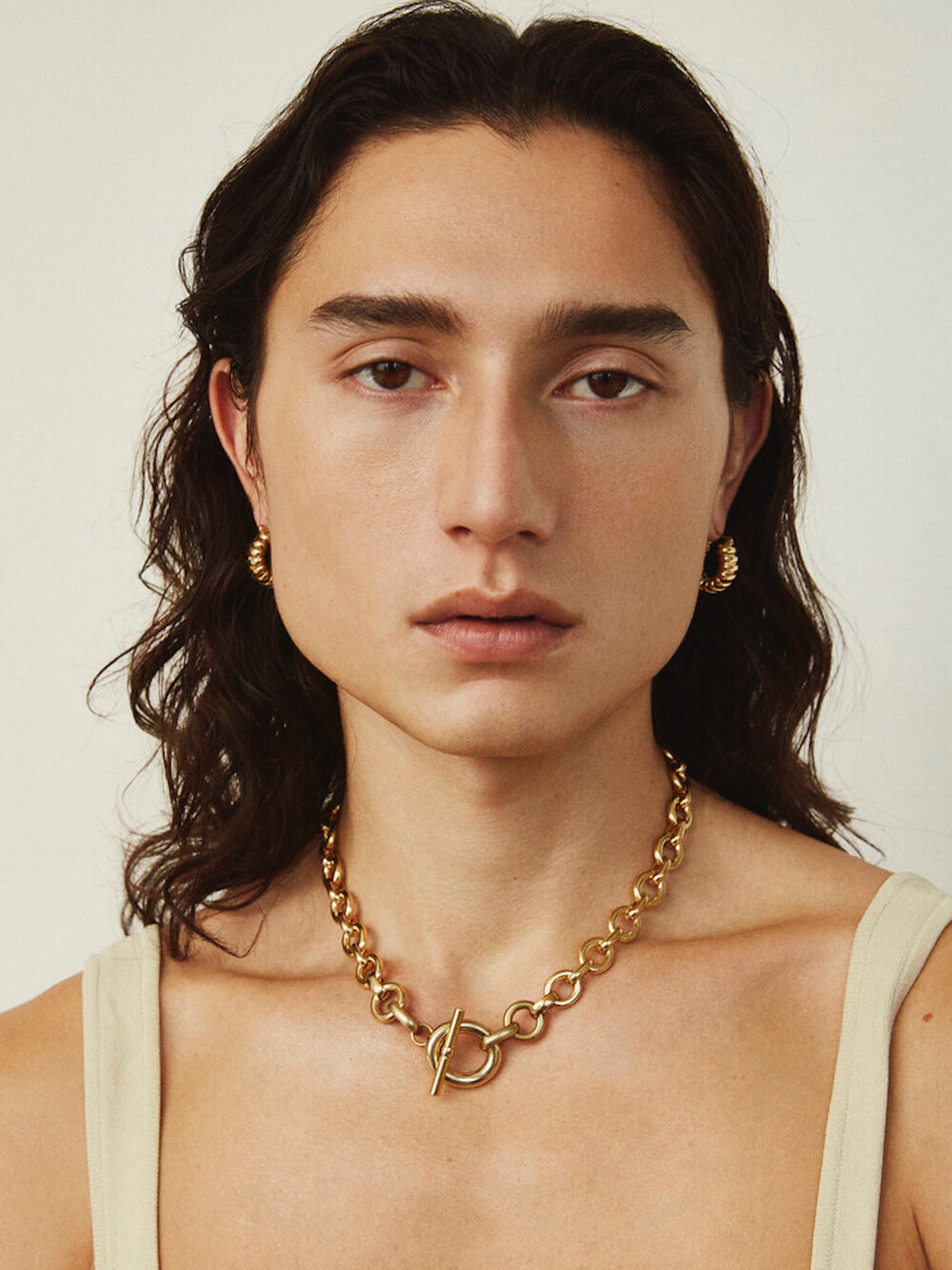 Model wearing Laura Lombardi gold Portrait Necklace with toggle clasp facing front.