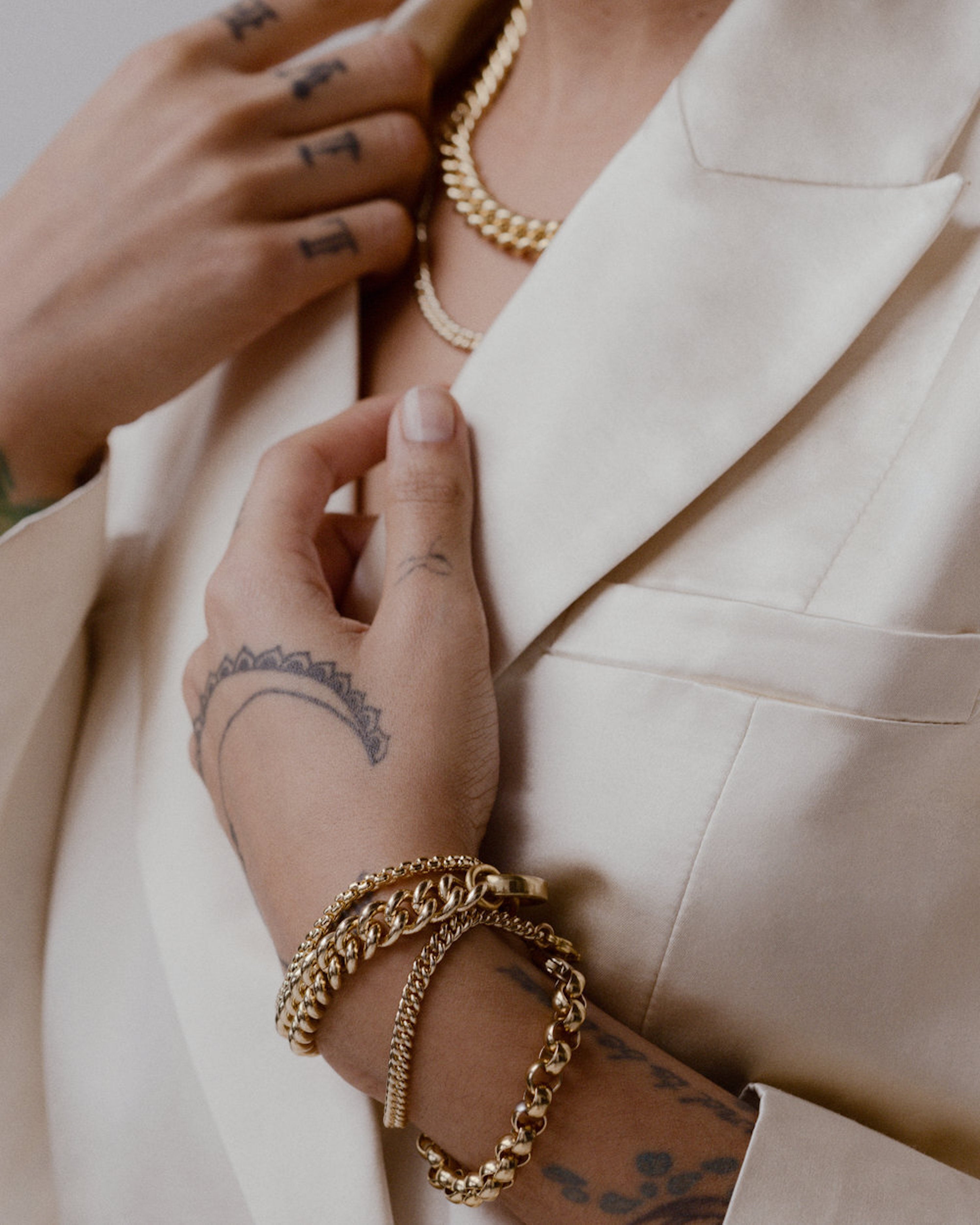 Model wearing layered Laura Lombardi gold chains.