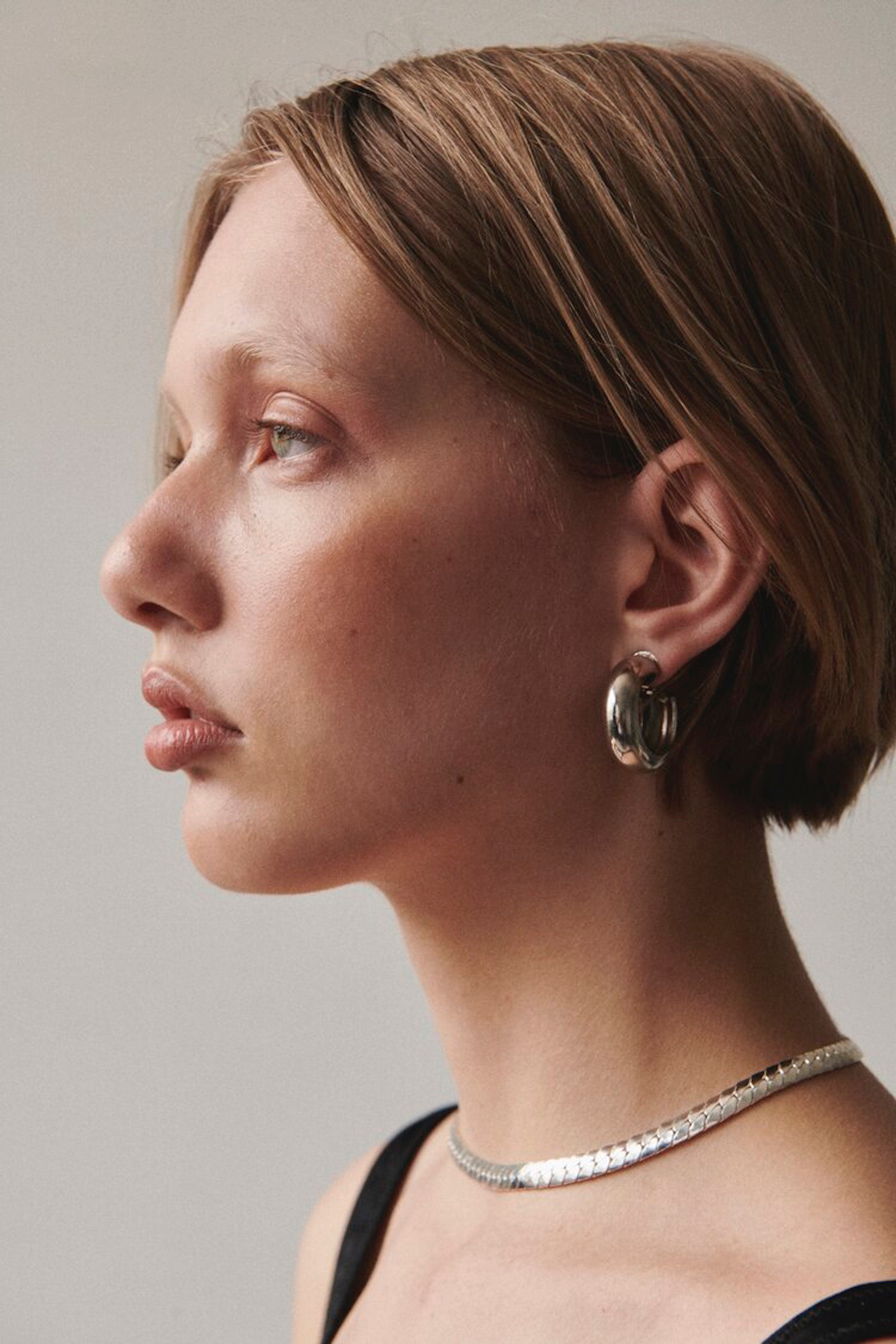 Side profile of model wearing Laura Lombardi silver Piatta Necklace and Cusp Hoops.