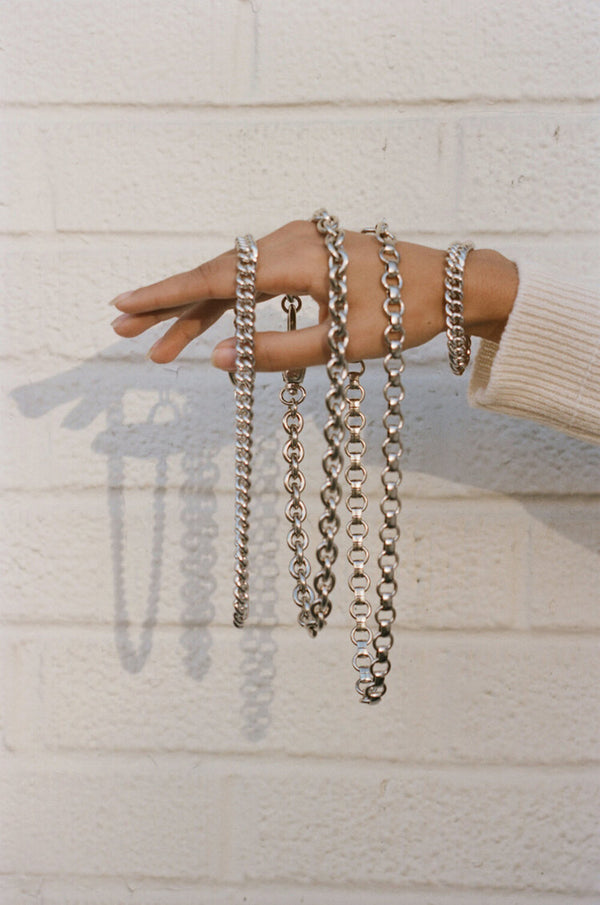 Model wearing Laura Lombardi Silver Presa Bracelet holding multiple silver chains.