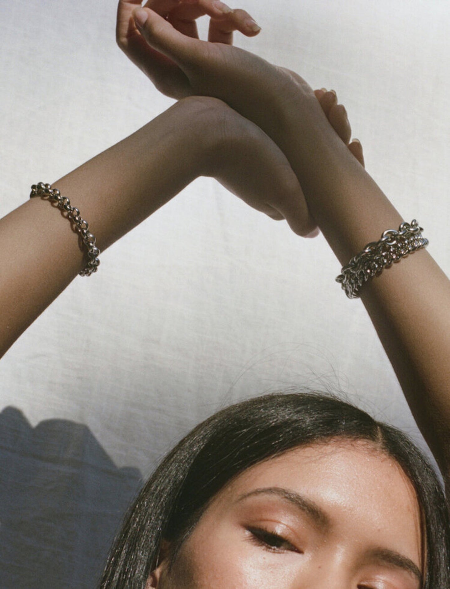 Model wearing layered Laura Lombardi silver bracelets.